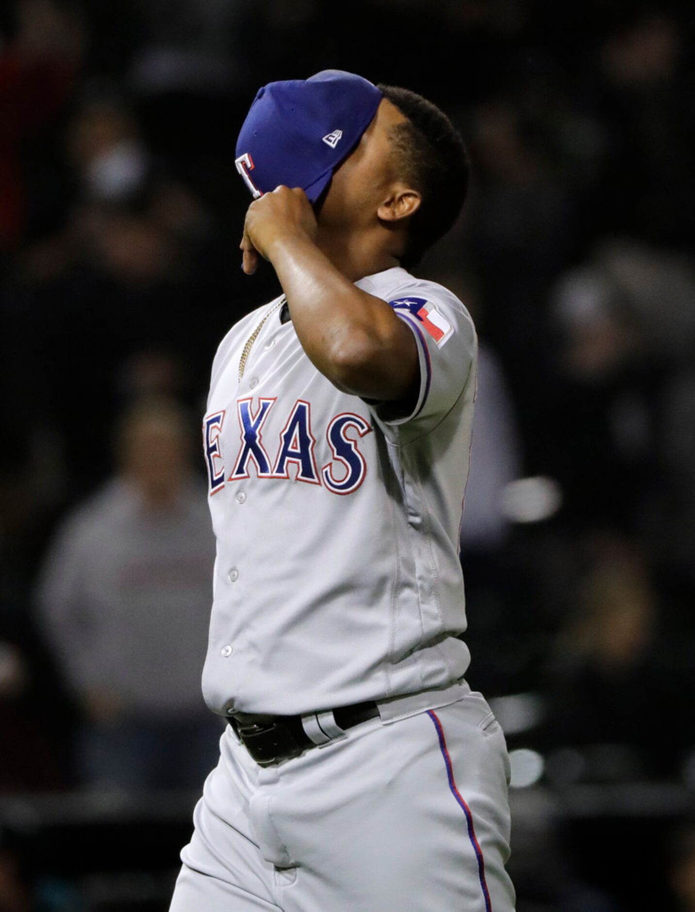 Texas Rangers relief pitcher Jose Leclerc covers his face with his cap as he leaves the...