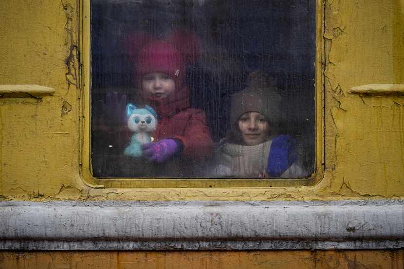 Children look out of the window of an unheated Lviv-bound train, in Kyiv, Ukraine. A growing...