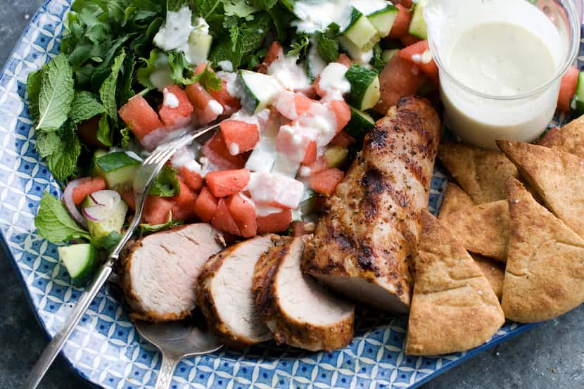 Grilled pork tenderloin with watermelon-arugula salad is shown served on a platter (AP...