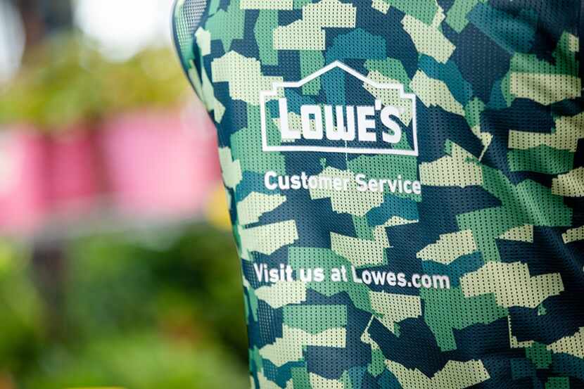 The rear view of a Lowe's employee's camouflage vest reads "Lowe's Customer Service" and...