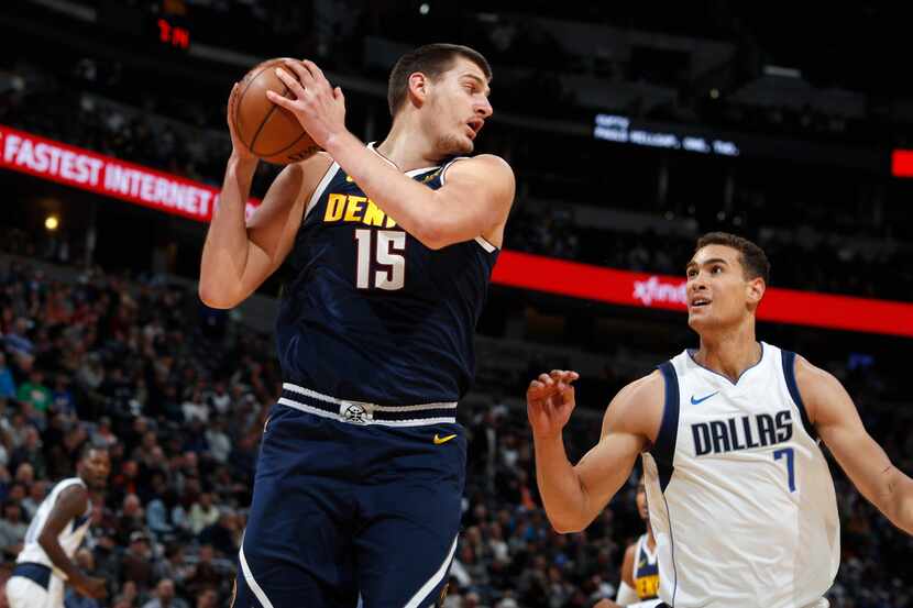 Denver Nuggets center Nikola Jokic, left, pulls in a rebound in front of Dallas Mavericks...