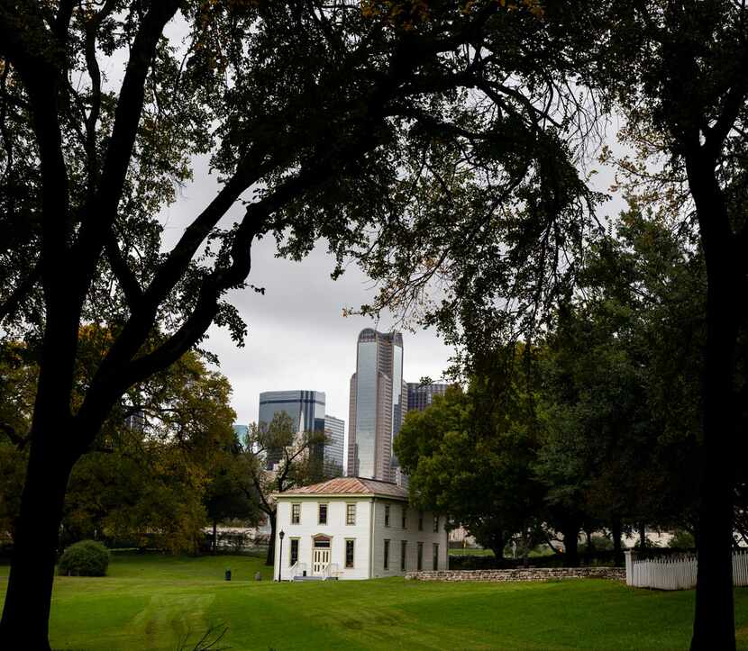 The downtown skyline looms over an old school house at Dallas Heritage Village at Old City...