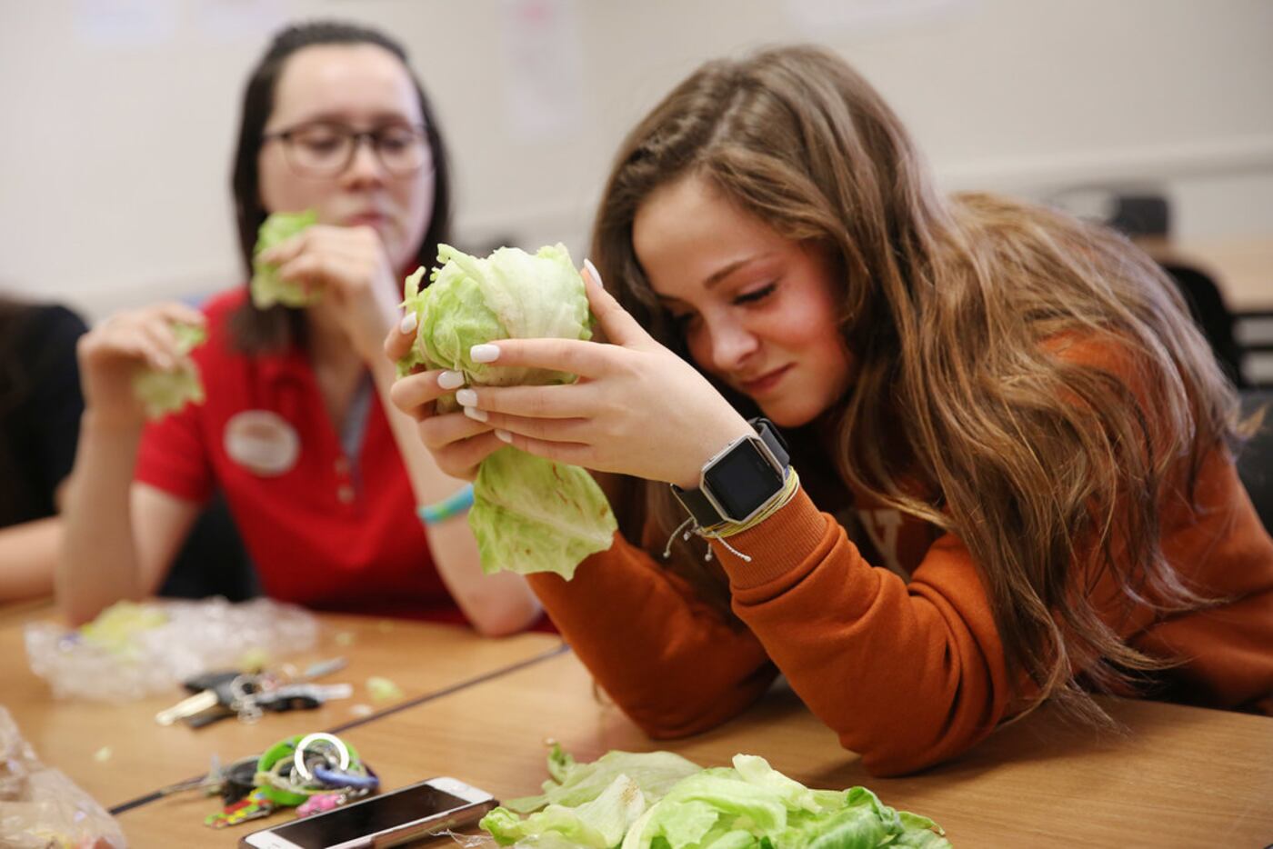 Senior Steph Halsey reacts while trying to eat a head of lettuce during a meeting of The...
