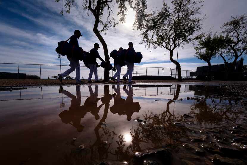 Texas Rangers players dodge puddles left over from the previous day's rains as they head for...