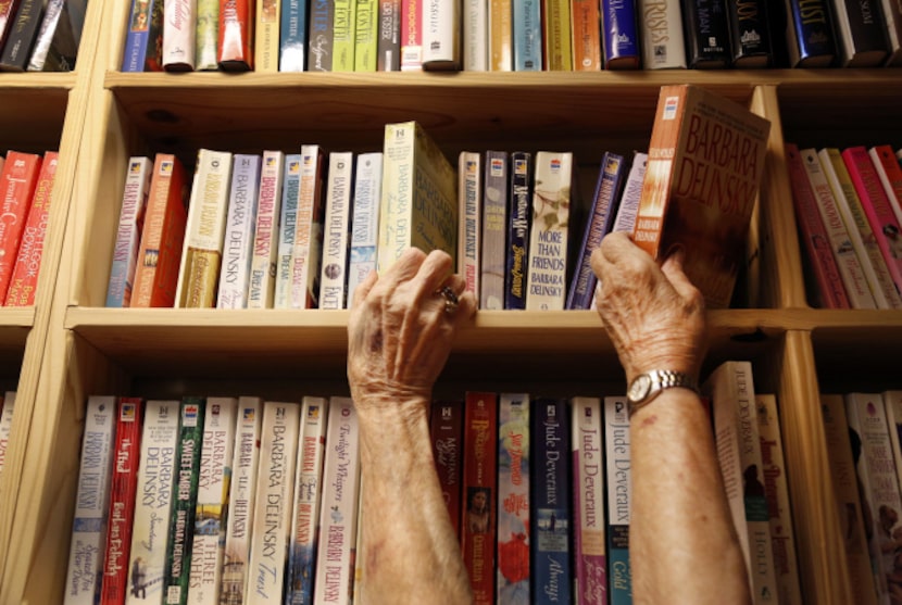 From L to R, Lucille Hopkins and Louise Kirby grab books from a same book shelf at the Lucky...