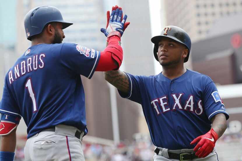 Texas Rangers' Elvis Andrus, left, high-fives Willie Calhoun on his two-run home run off...