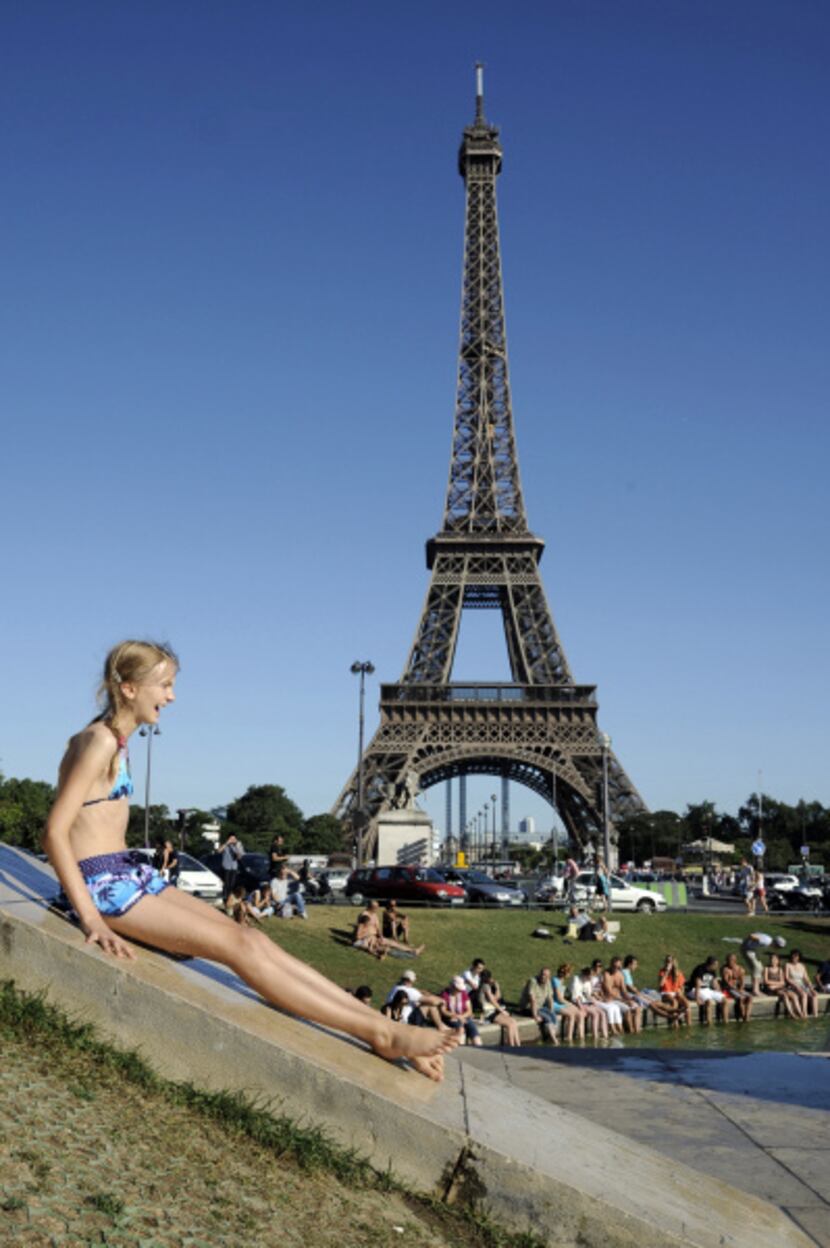 A girl slides to cool off in the Trocadero's fountains in front of the Eiffel Tower, on...