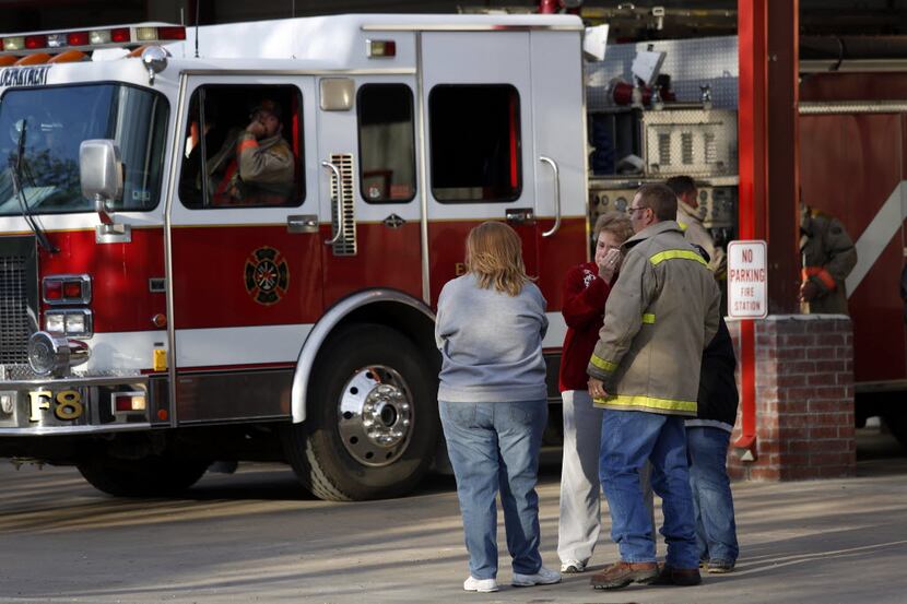 Residents and firefighters console each other outside the West Volunteer Fire Department in...