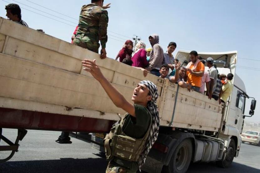
Members of Iraq’s Yazidi minority who fled their homes in Sinjar are transported by truck...