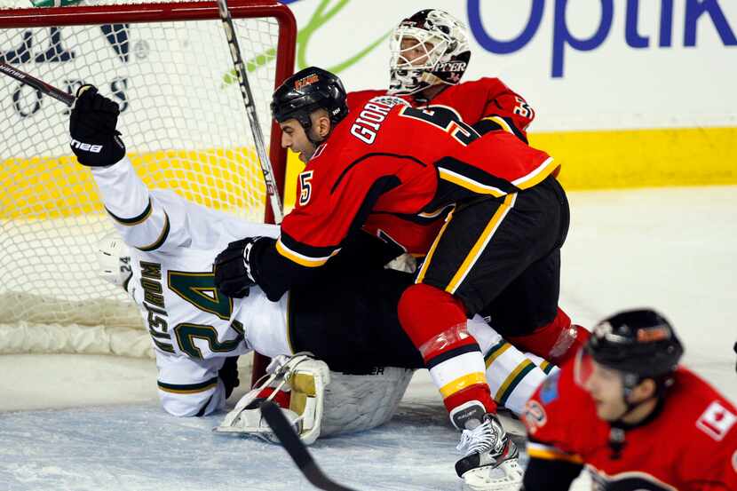 Dallas Stars' Eric Nystrom, left, gets tackled by Calgary Flames' Mark Giordano, center, in...