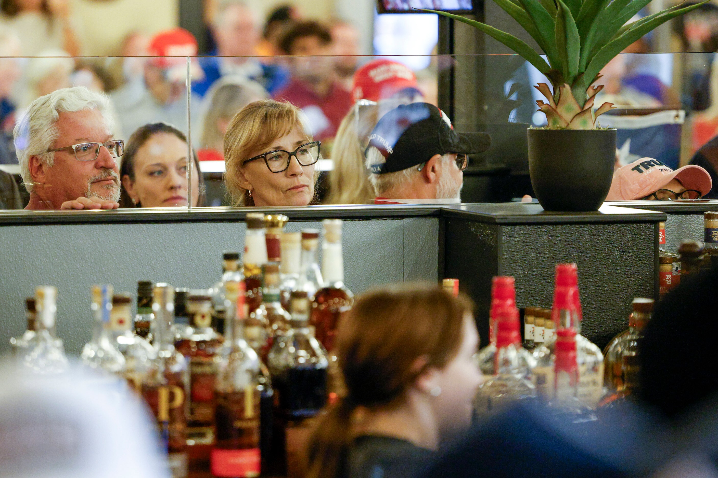 People peer over the bar at Outpost 36 BBQ to watch Senator Ted Cruz (R-Texas) during a...