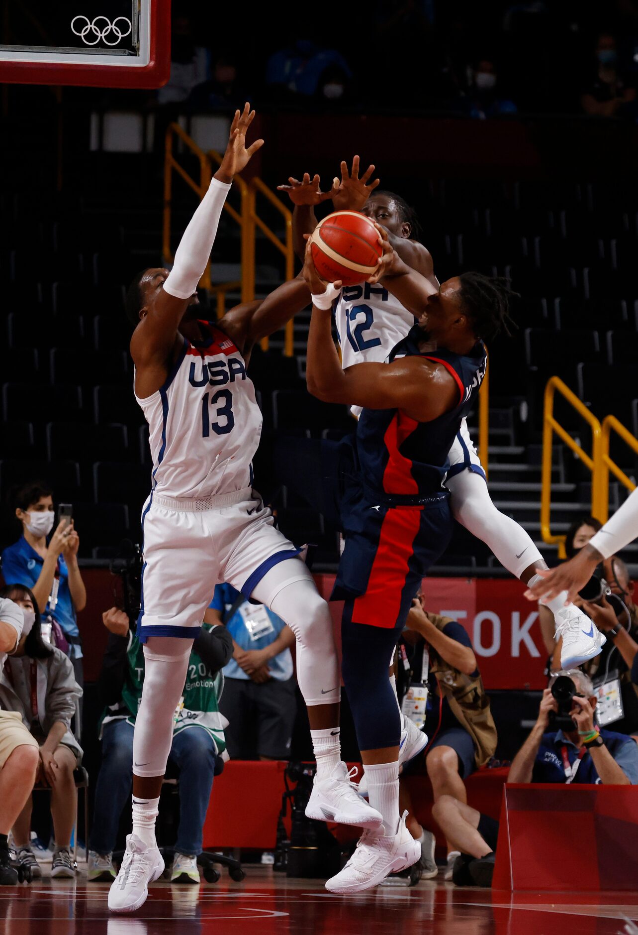 USA’s Bam Adebayo (13) and Jrue Holiday (12) defends as France’s Guerschon Yabusele (7)...