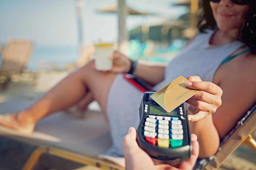 Una mujer paga con una tarjeta de crédito una bebida en un destino turístico.(GETTY IMAGES)
