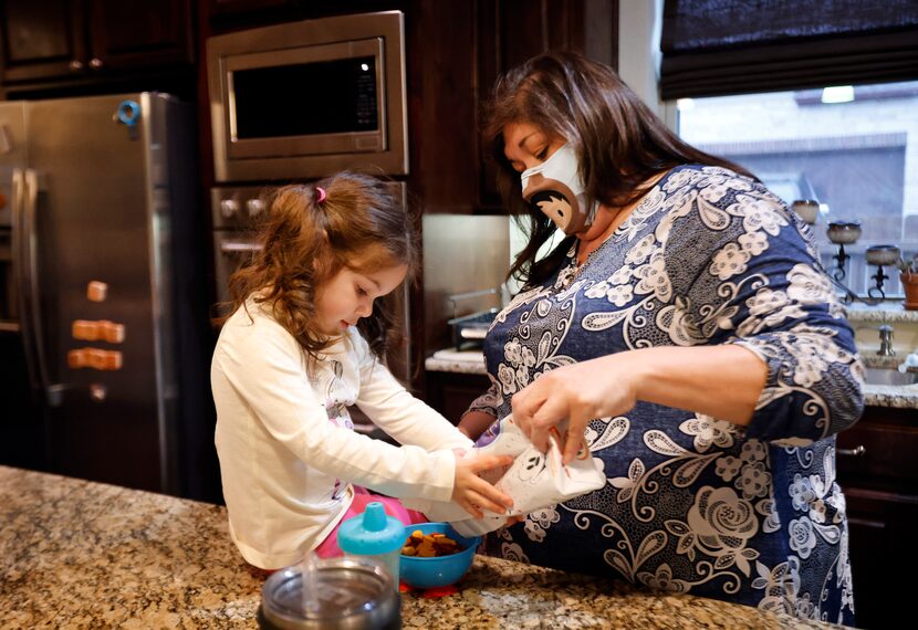 Carmen Lozoya pours a snack for granddaughter Esme Bueno Galindo, 3, during an overnight...