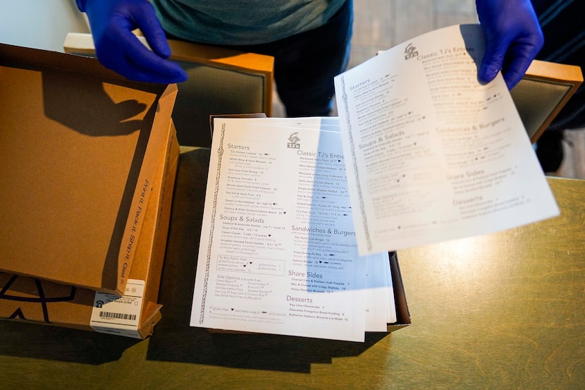 Bar manager Brett Martin unboxes new disposable menus at TJ's Seafood restaurant on Tuesday...