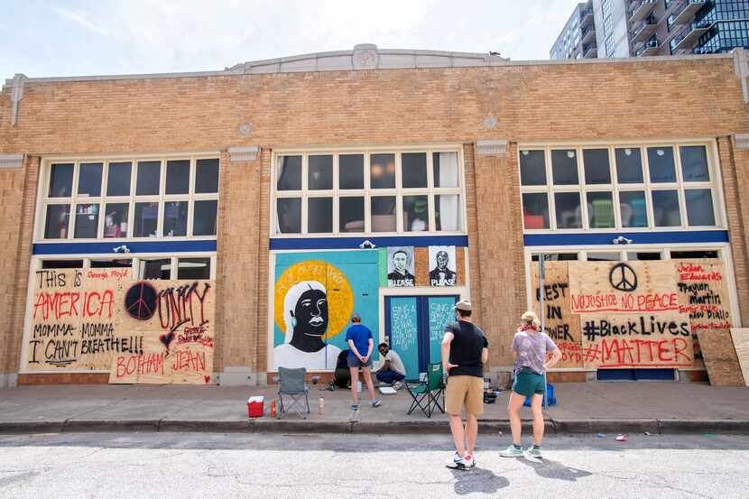 Friends watch Desiree Vaniecia and Joeneal Berry paint a mural on plywood on Monday, June 1,...
