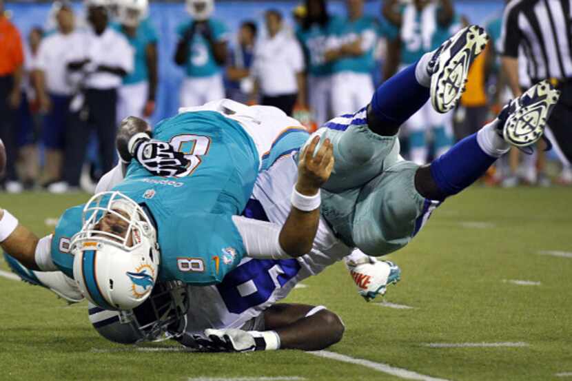 Miami Dolphins quarterback Matt Moore (8) winces as he is sacked and rolled up by Dallas...