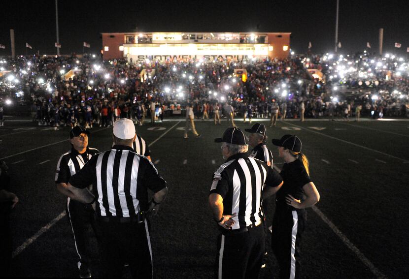 Game officials wait for the stadium lights to come back on after they cut out during the...
