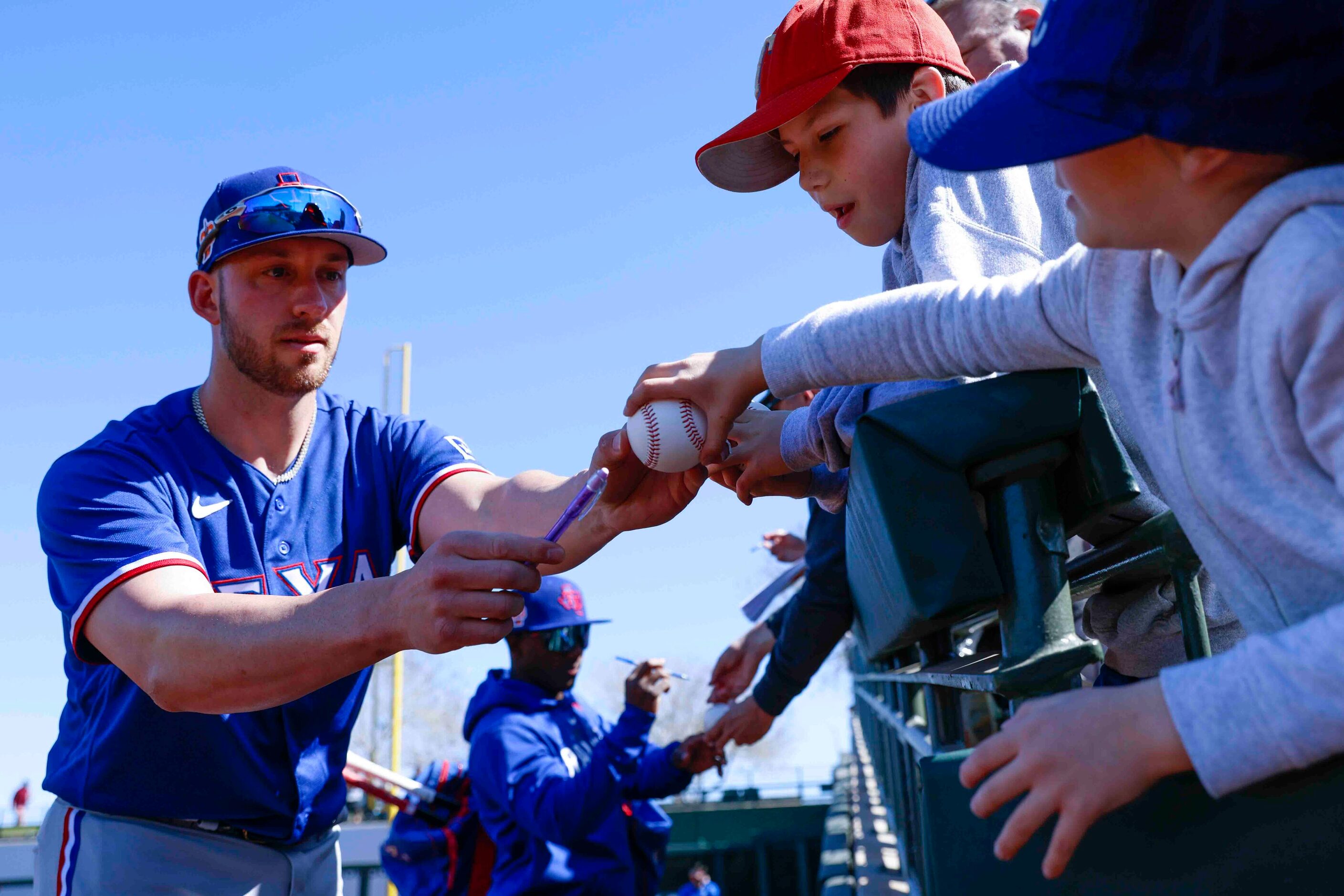 Texas Rangers catcher Mitch Garver signs autograph to fans before a spring training game...