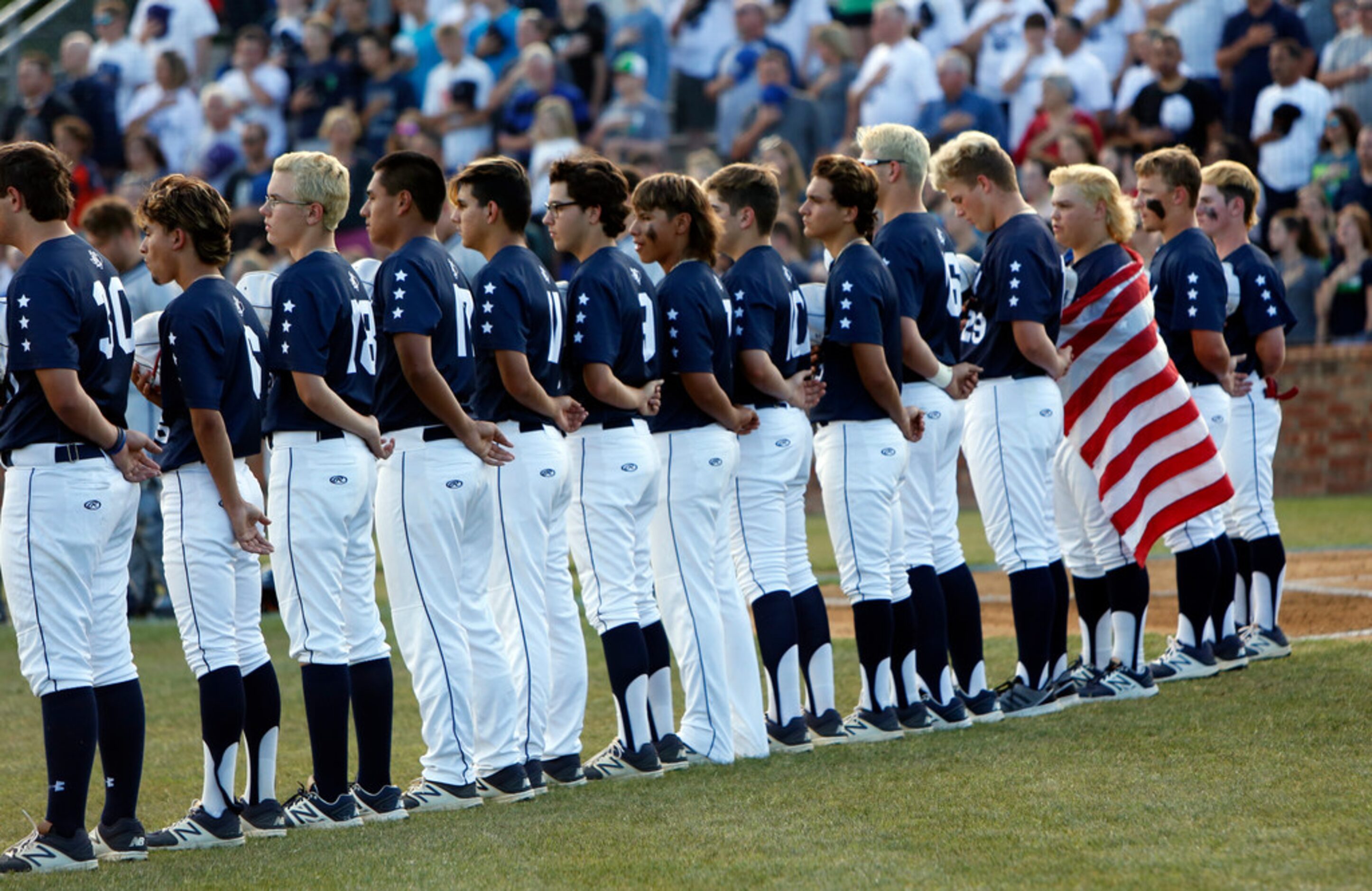 Richland players pause for the playing of the national anthem prior to the start of their...