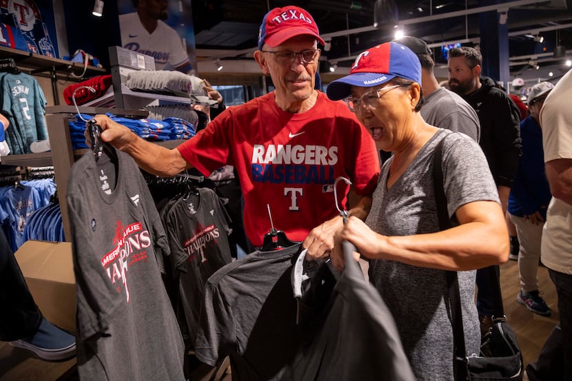 Rangers fans Randy Keadey (left) and wife Yong Hong look at American League Champions shirts...