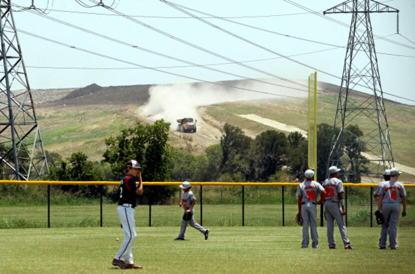 With the DFW Landfill as a backdrop, baseball teams warm up before a game at Railroad Park...
