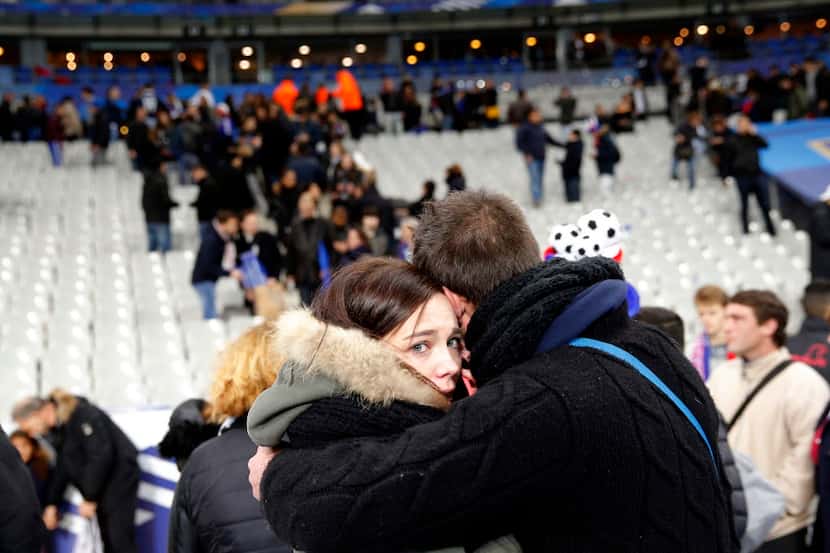 Spectators embrace each other as they stand on the playing field of the Stade de France...