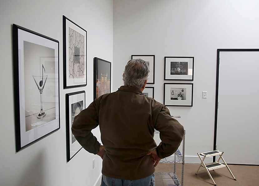  Burt Finger pauses to consider a grouping as he hangs work at Photographs Do Not Bend...
