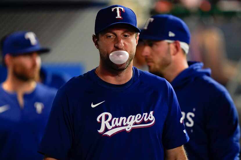 Texas Rangers pitcher Max Scherzer blows a gum bubble in the dugout during the second inning...