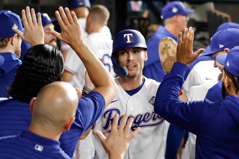 Texas Rangers' Evan Carter celebrates in the dugout after scoring on a base hit by Adolis...