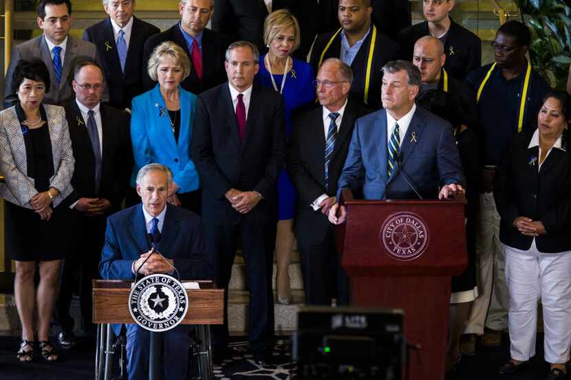 Texas Governor Greg Abbott (front, left) and Dallas Mayor Mike Rawlings (right) speak during...