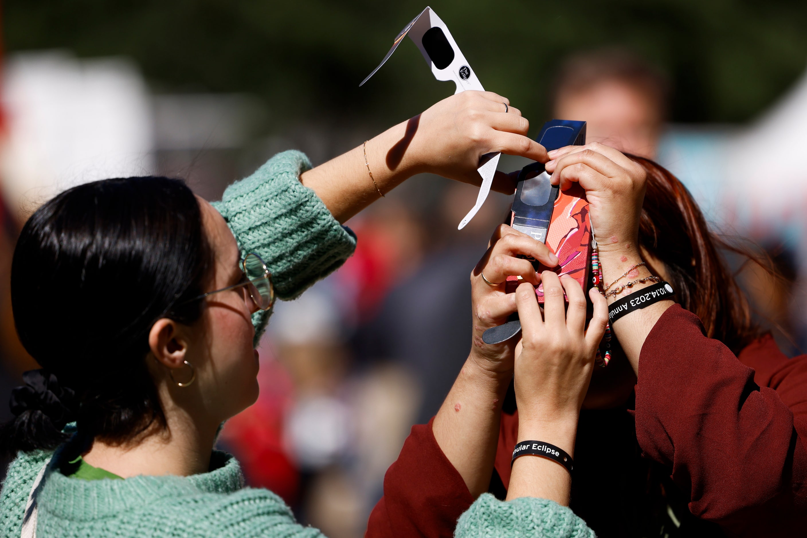 Sam Ordonez (left) helps Jandy Cuellar of Dallas to take a photo of the annular solar...