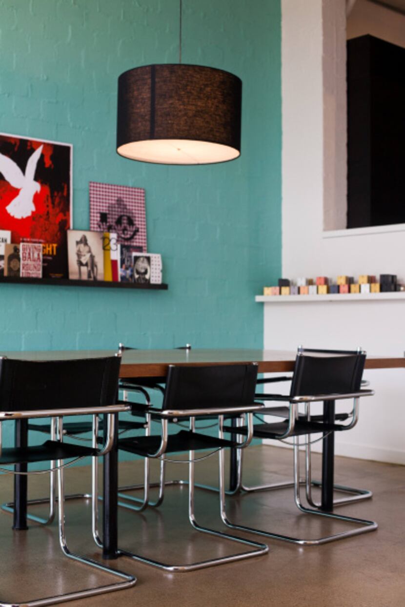 Black drum pendant lights and turquoise walls enliven a conference room.