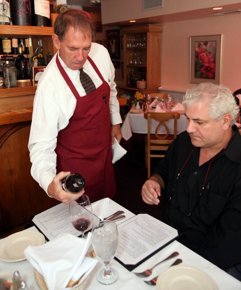 Ferando Colli, (L), pours a bottle of red wine for Massimo Ramundi at Adelmo's Ristorante.