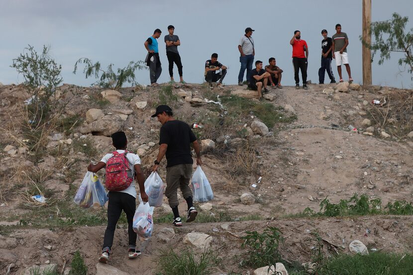 EL PASO— A group of migrants gathers in front of a Border Patrol vehicle at the banks of the...