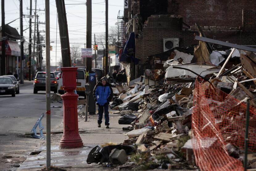A man walks past a small commercial strip that burned down during Superstorm Sandy in the...
