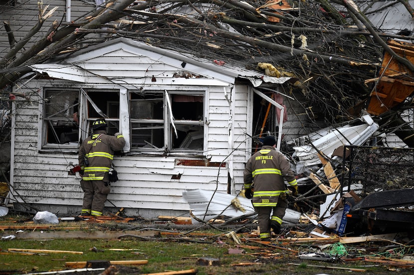 Members of the Huntsville Volunteer Fire Department search damaged homes following a severe...