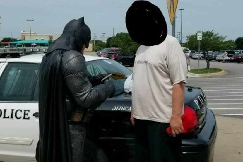 Officer Damon Cole, dressed as Batman, gives a citation to a man accused of shoplifting at...