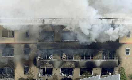 Firefighters work as smoke billows from a three-story building of Kyoto Animation in a fire...
