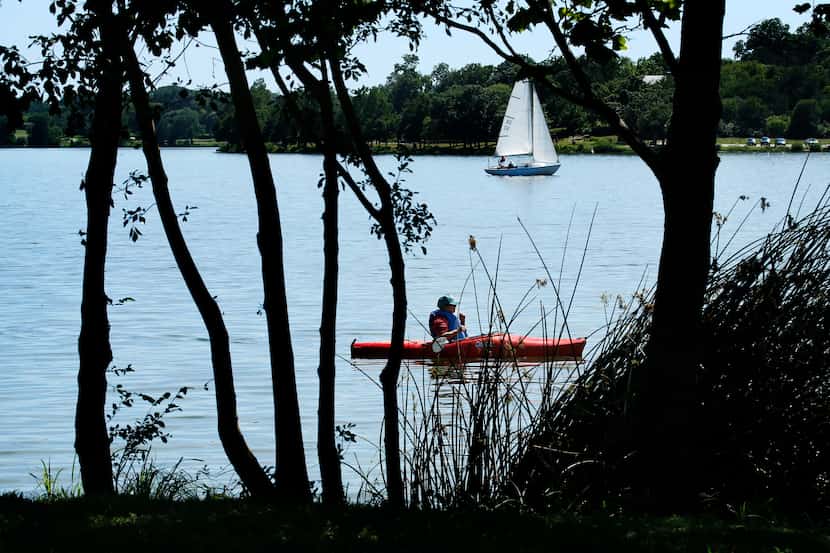 A kayaker and sailboat take to the water at Dallas' White Rock Lake.