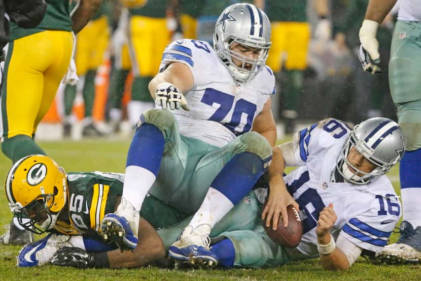 Dallas Cowboys guard Zack Martin (70) ends up seated on top of quarterback Matt Cassel (16)...
