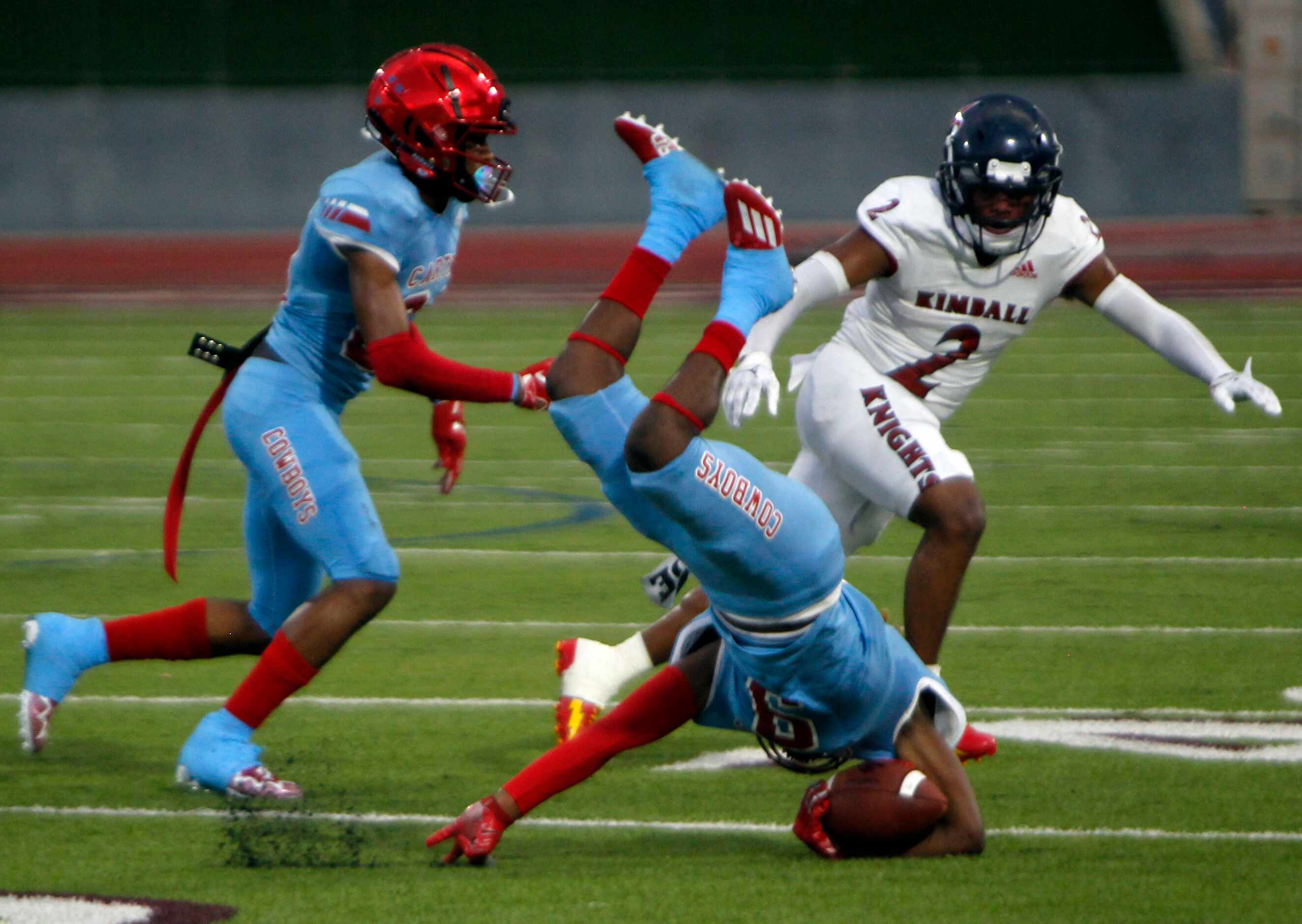 Dallas Carter's Khyion Andrews (9) takes a nose dive after slipping on the wet turf making a...