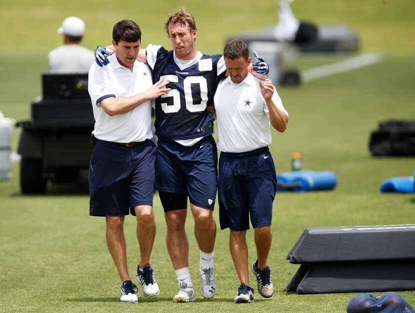 Dallas Cowboys Sean Lee is helped off the field by Dallas Cowboys head athletic trainer Jim...