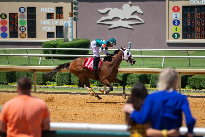 Fans look on as Weekend Madness, ridden by Ramon Vazquez, wins a race at Lone Star Park in...