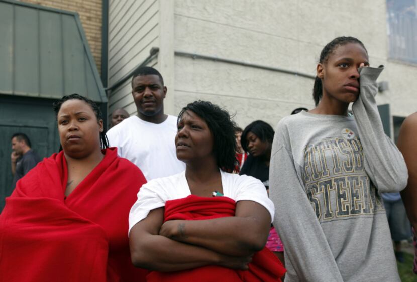 Residents including Amy Dixon (center) watched as firefighters carried the fallen...