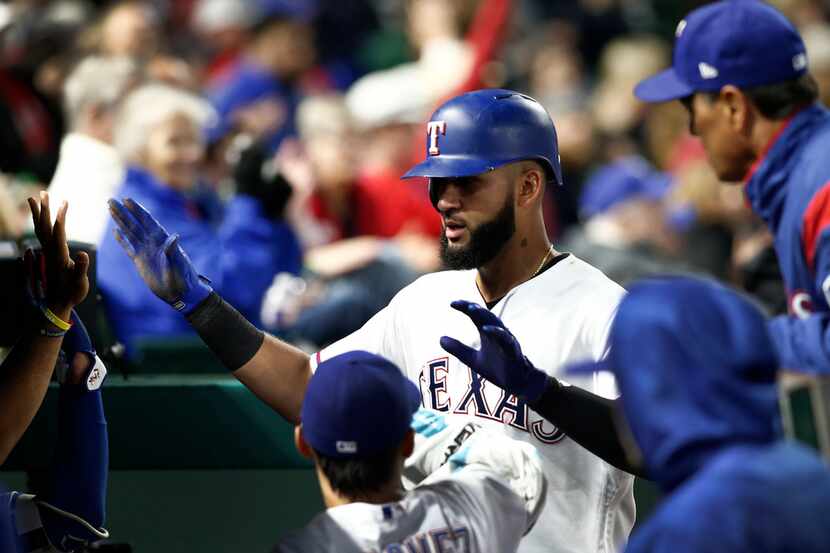 Texas Rangers' Nomar Mazara is congratulated by teammates after scoring during the fifth...