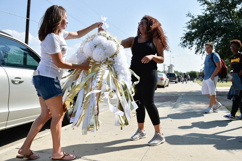 Sherry Bedinger, the chair of the Denton High School mum fundraiser, hands a mum to student...