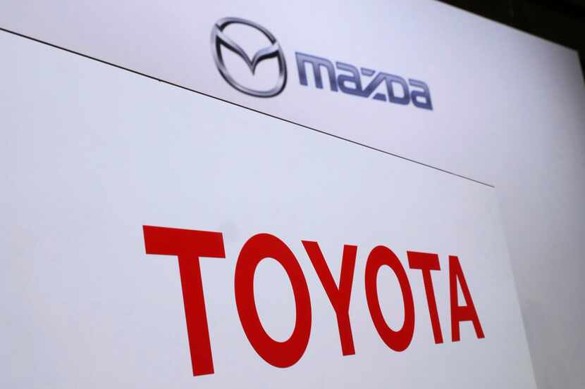 FILE- In this Aug. 4, 2017, file photo, logos of Toyota Motor Corp., bottom, and Mazda Motor...