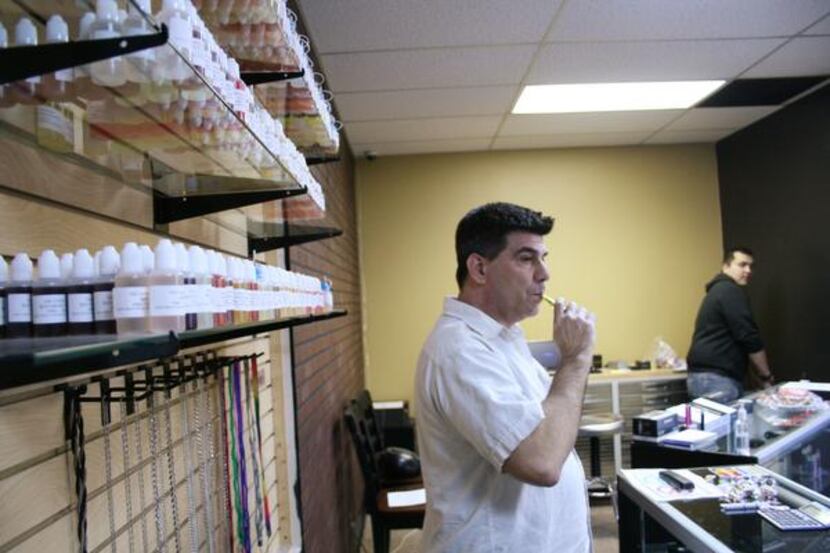 Frank Malara takes a puff of vapor from his e-cigarette while standing in front of an...