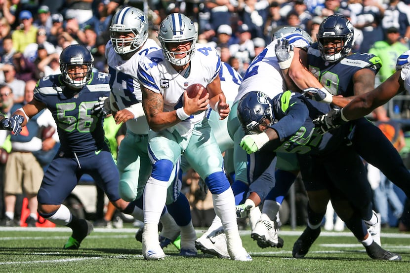 Dallas Cowboys quarterback Dak Prescott (4) escapes a tackle from Seattle Seahawks defensive...